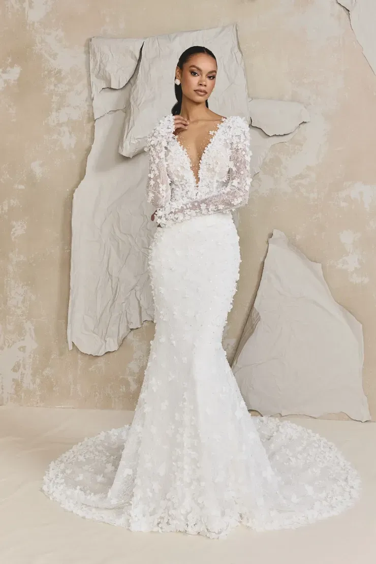 A woman is wearing a white wedding dress with long sleeves and a plunging neckline.