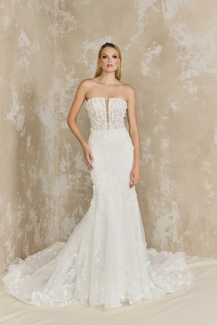 A woman in a white wedding dress is standing in front of a wall.