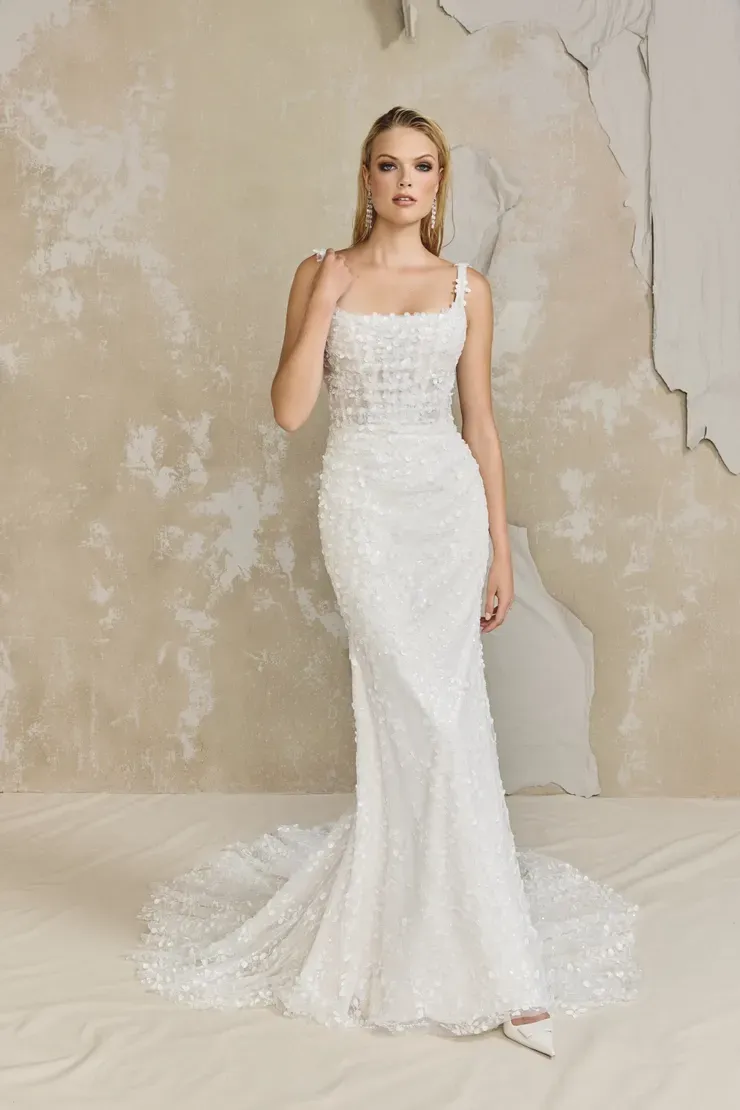 A woman in a white wedding dress is standing in front of a wall.