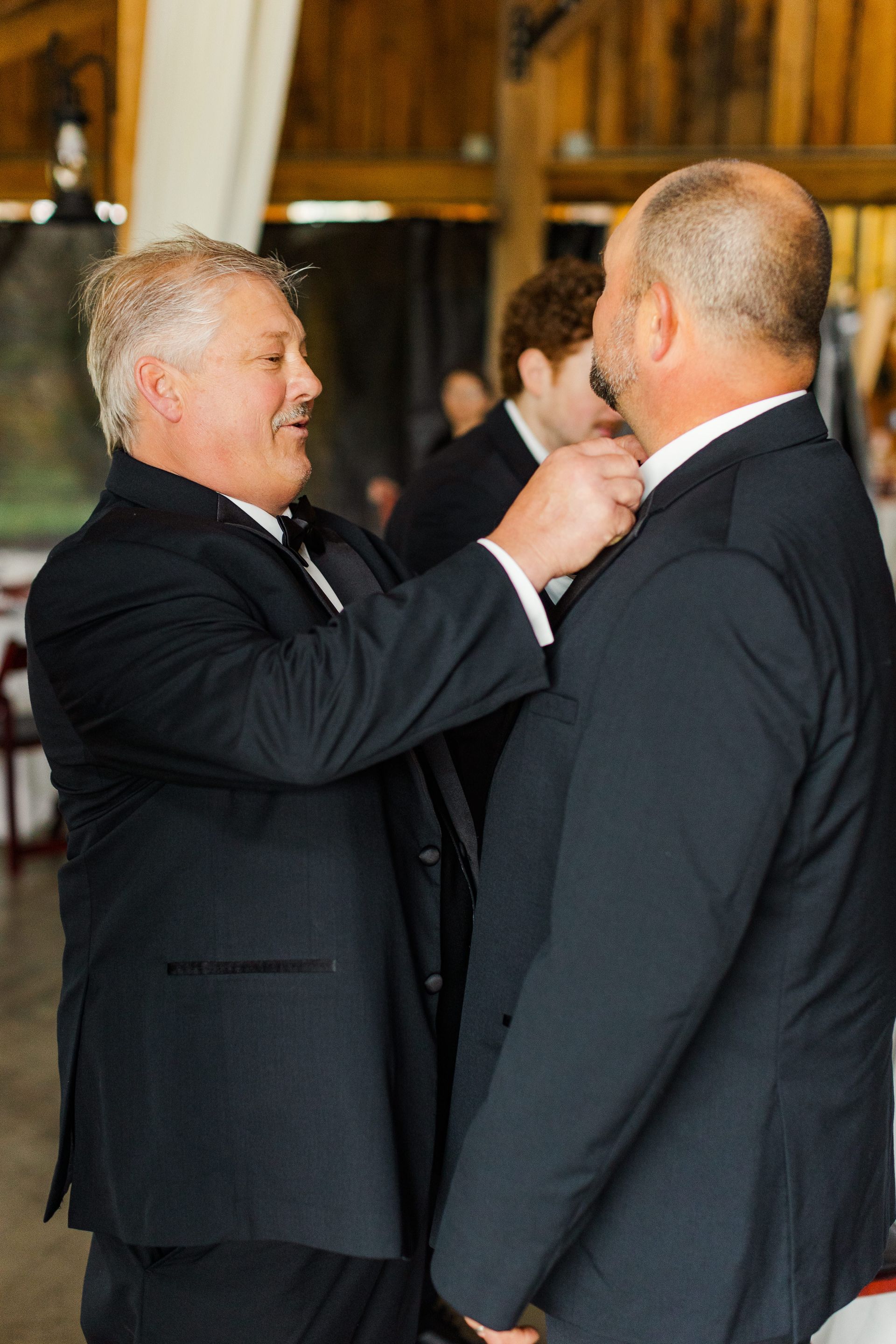 A man in a suit is helping another man with his tie.