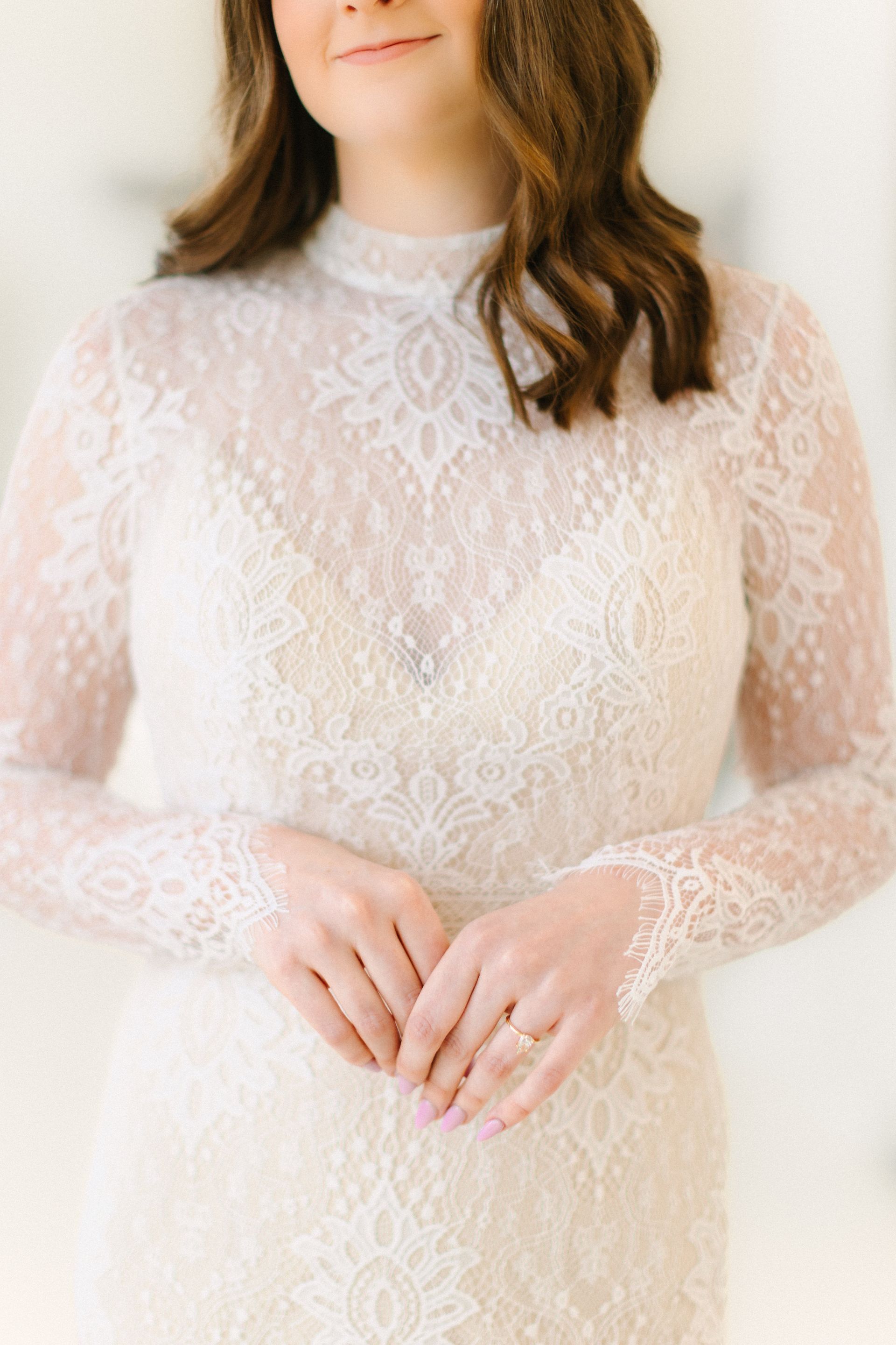 A woman is wearing a white lace dress with long sleeves.