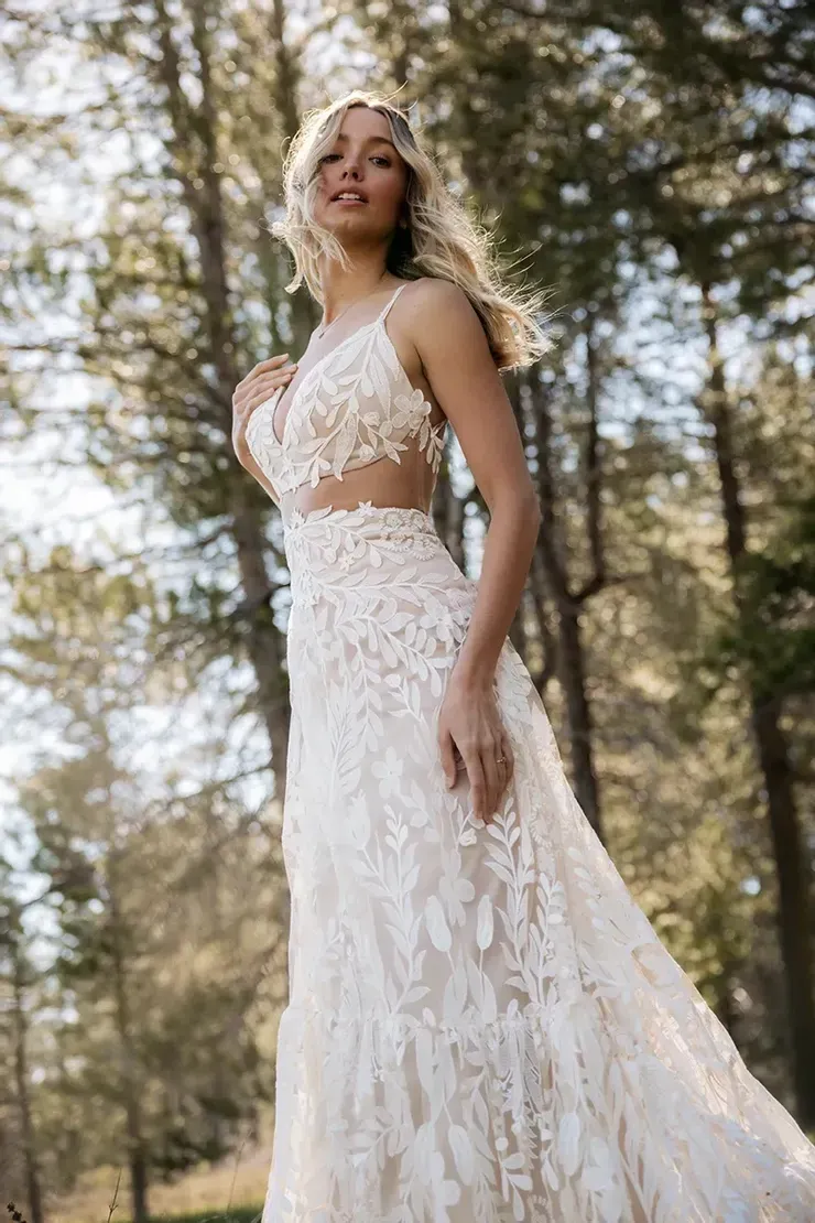 A woman in a wedding dress is standing in the woods.