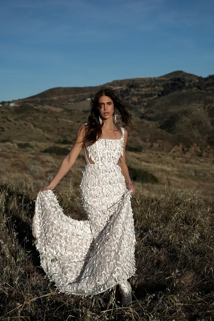 A woman in a white dress is standing in a field.