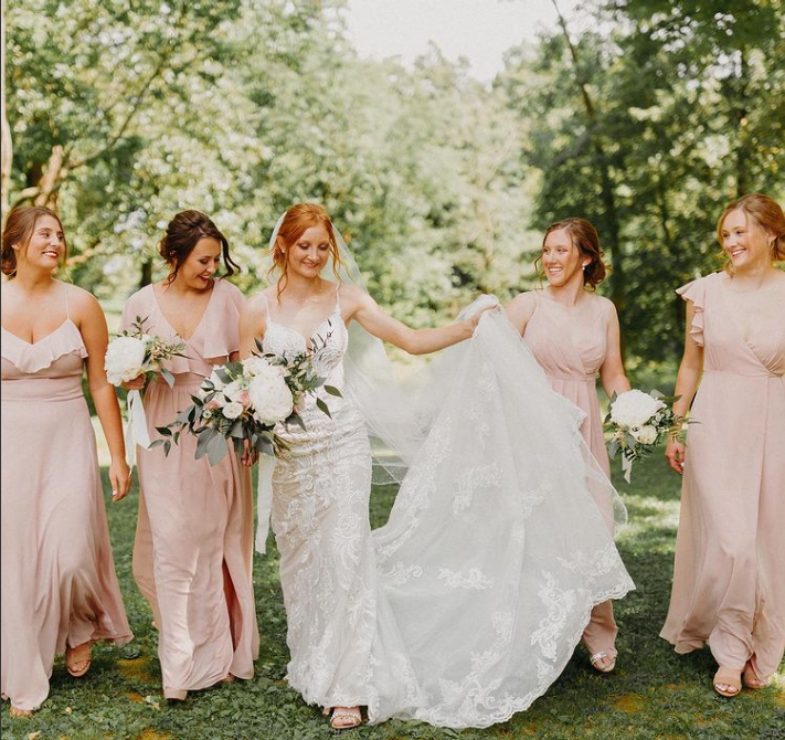 A bride and her bridesmaids are walking in a field