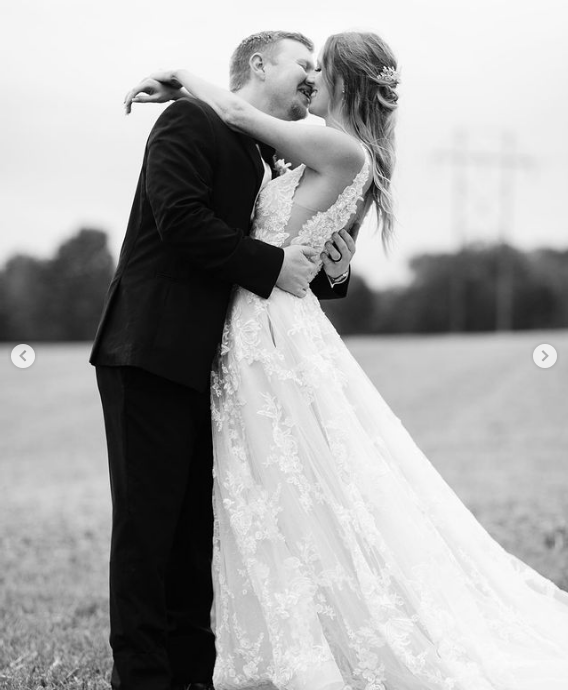 A bride and groom are kissing in a field in a black and white photo.