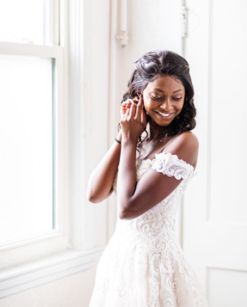 A woman in a wedding dress is putting on her earrings.