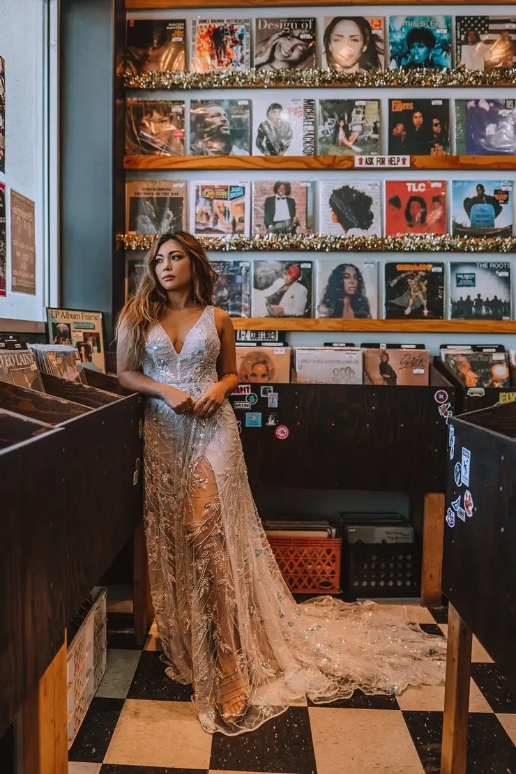 A woman in a wedding dress is standing in a record store.