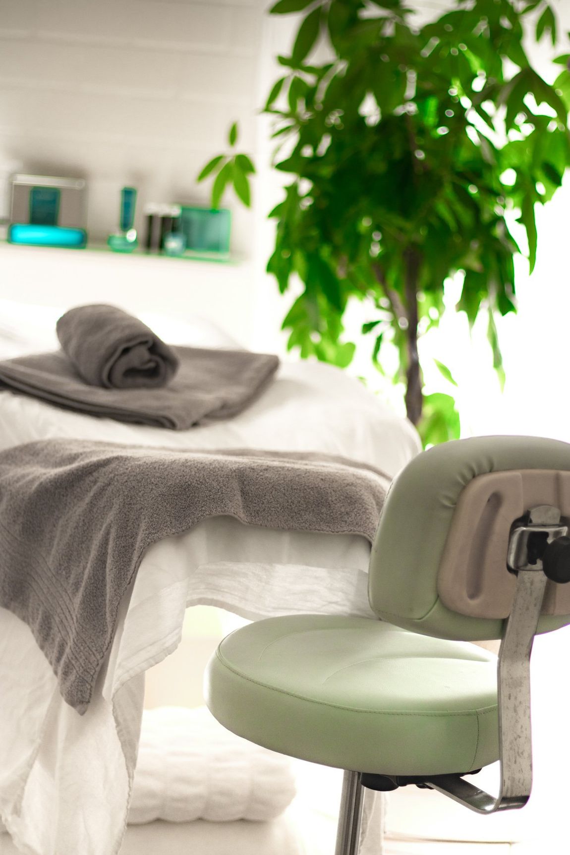 Vor einem Massagetisch steht ein Stuhl mit Handtüchern darauf.