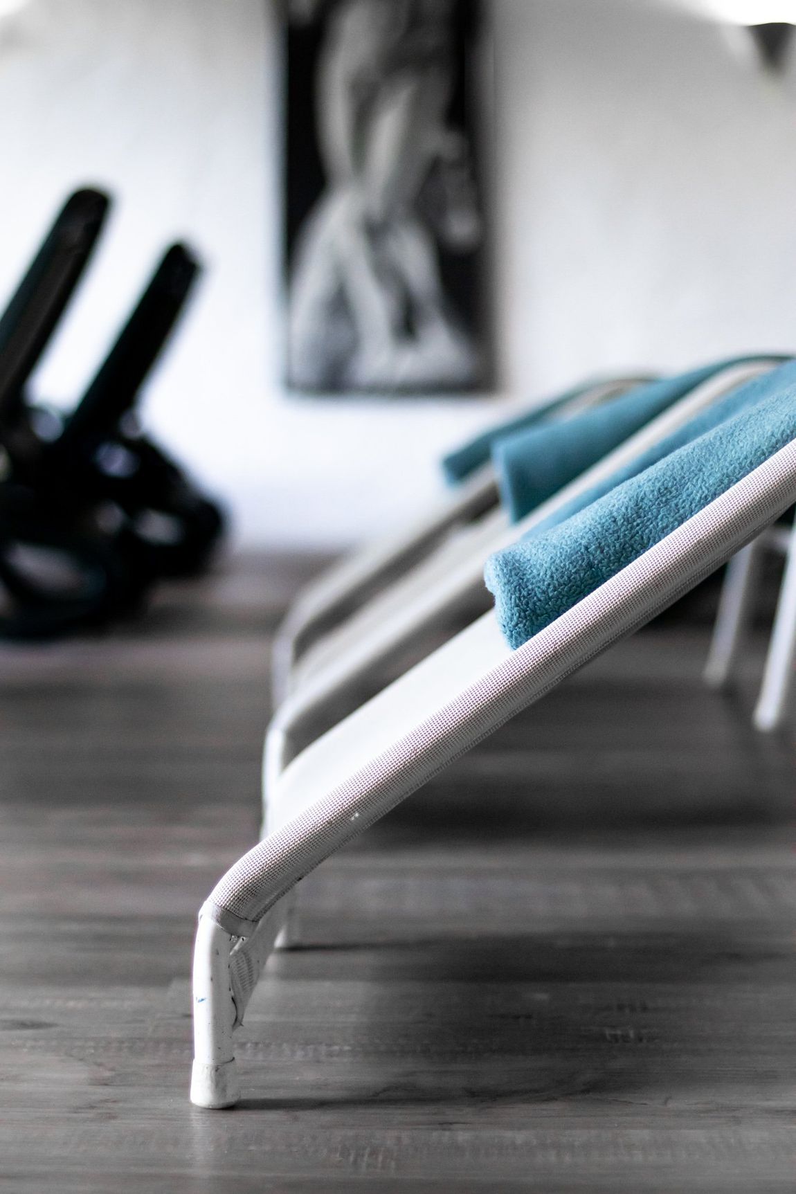 Eine Reihe von Liegestühlen mit blauen Handtüchern darauf in einem Fitnessstudio.