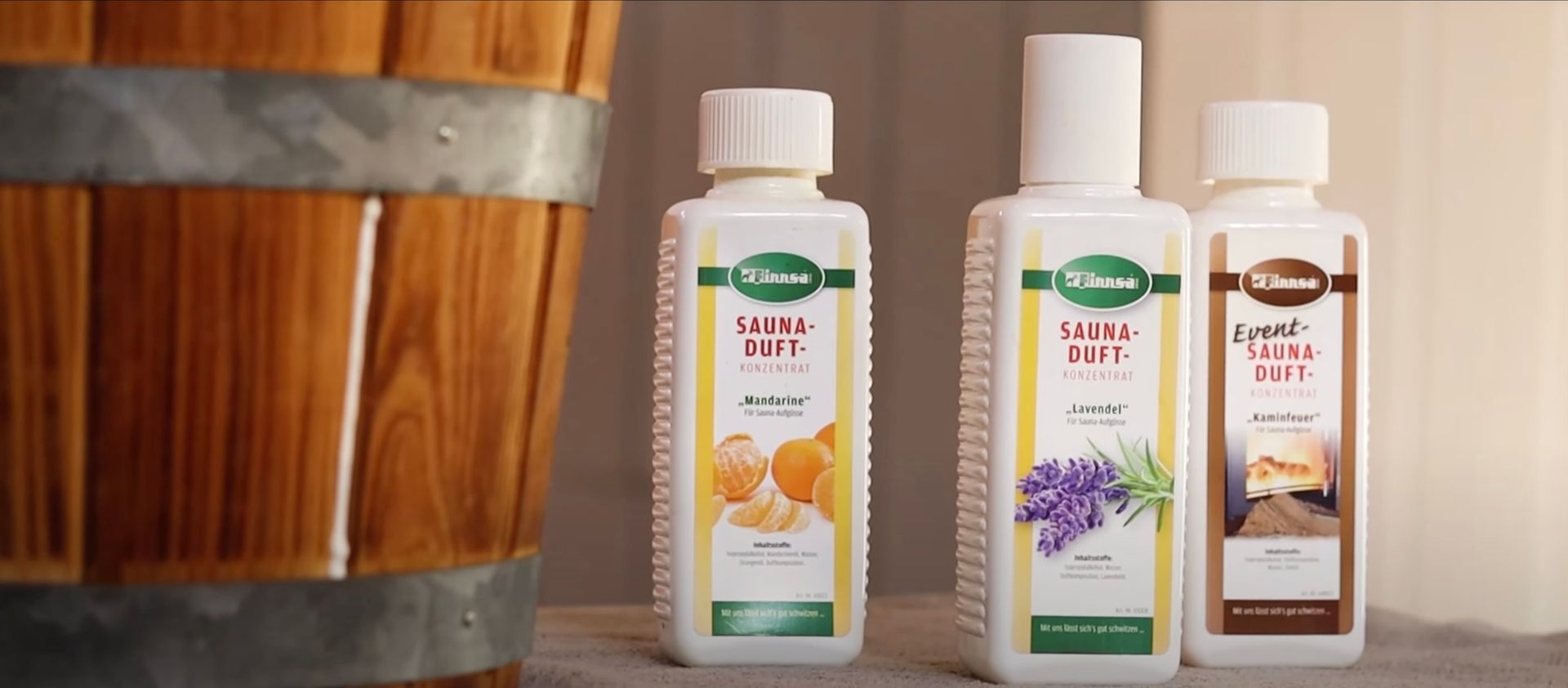 Drei Flaschen Lotion stehen neben einem Holzfass