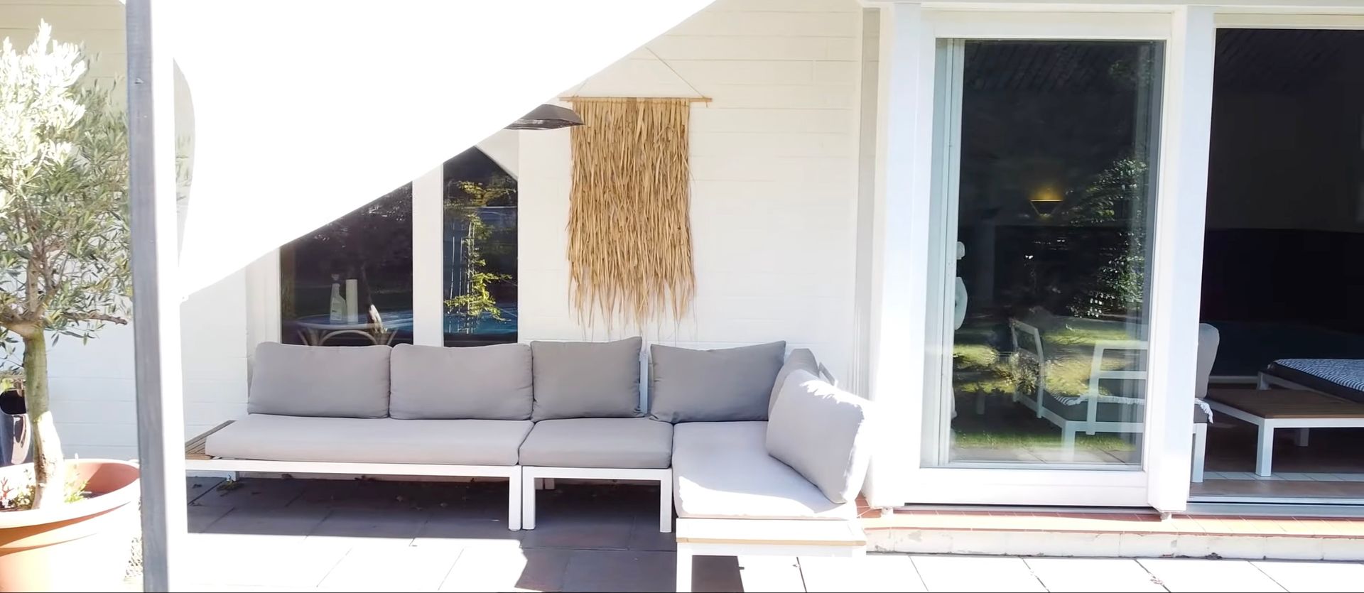 Eine Terrasse mit einer Couch und einer Glasschiebetür