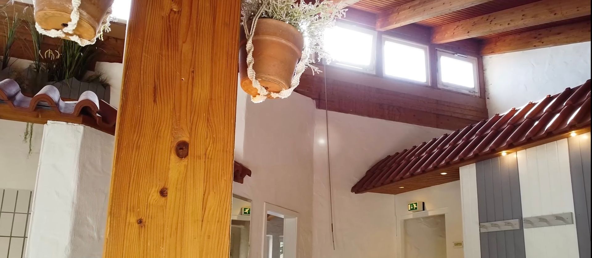 Ein Raum mit einer Holzsäule und Topfpflanzen, die von der Decke hängen.