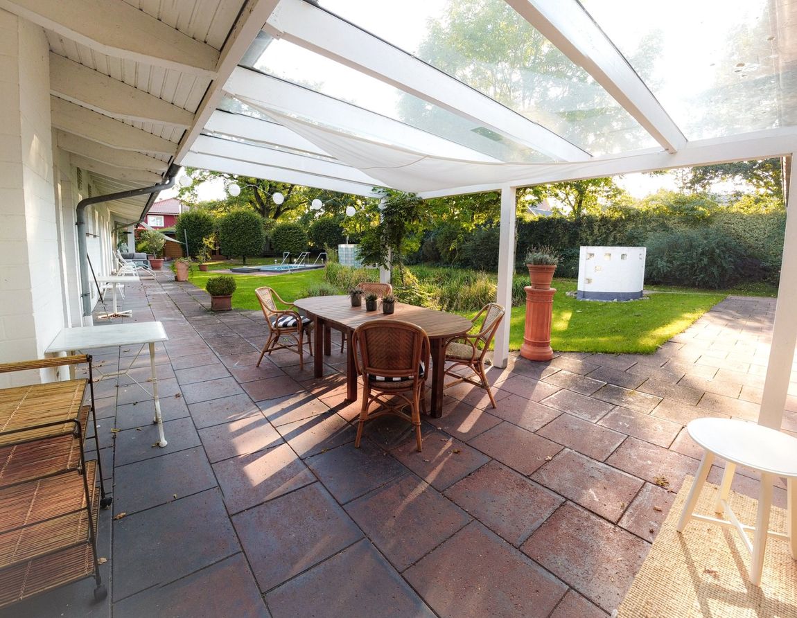Eine Terrasse mit Tisch und Stühlen unter einem durchsichtigen Dach