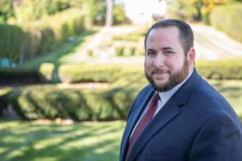 a man in a suit and tie is standing in a park .