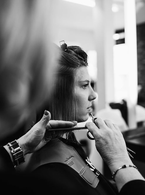 Coiffeur coiffant les cheveux d'une personne avec un fer à friser dans un salon