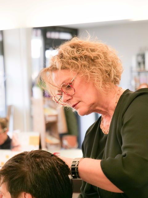 Coiffeuse coupant les cheveux d'une cliente dans un salon lumineux