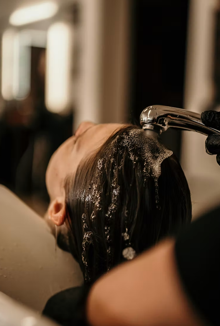 Cheveux rincés au lavabo d'un salon de coiffure, l'eau coulant sur le cuir chevelu
