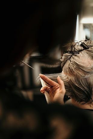 Personne aux cheveux courts tenant une cigarette près du visage dans un intérieur sombre et flou
