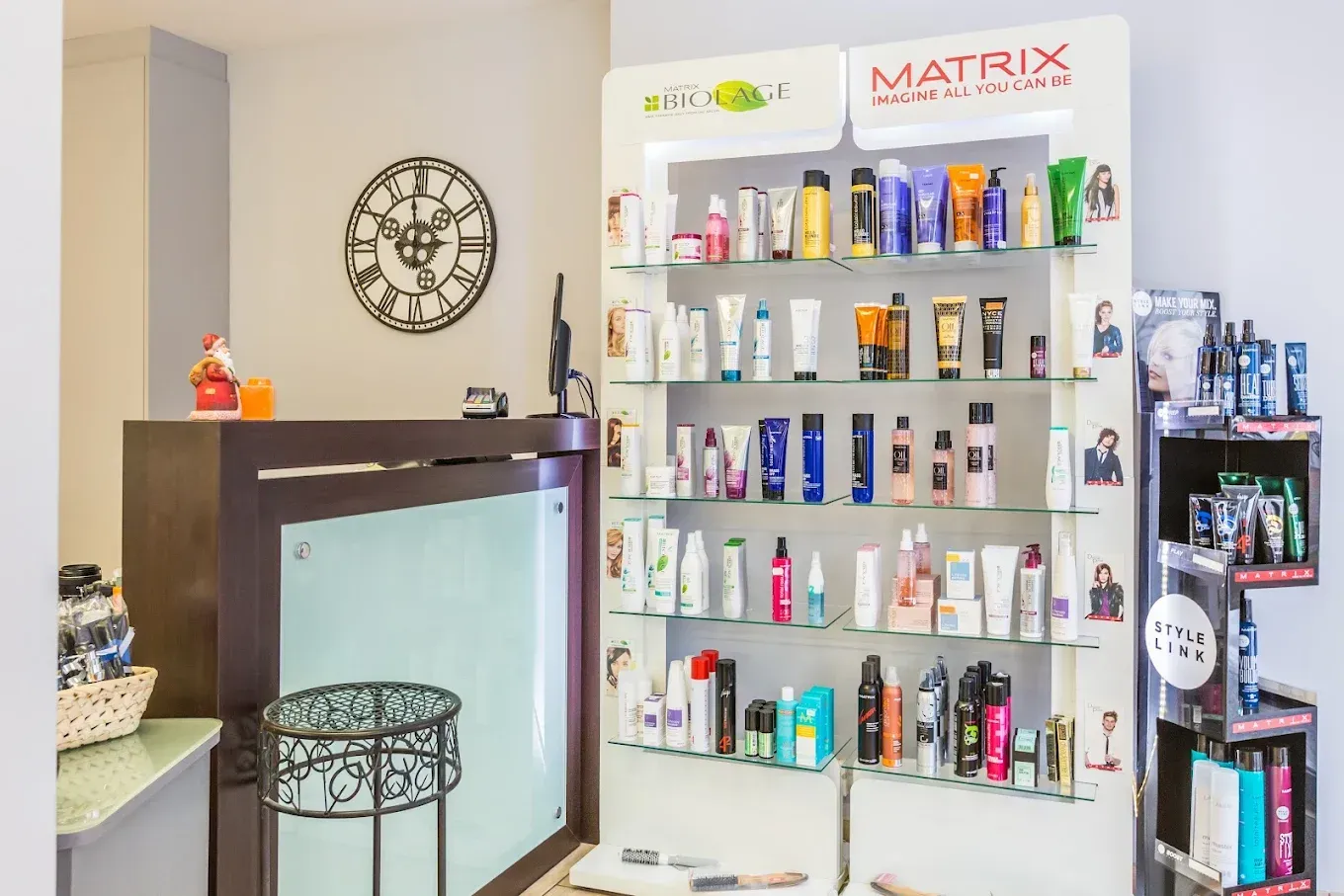 Intérieur d'un salon de coiffure avec étagères à produits, comptoir d'accueil et horloge murale