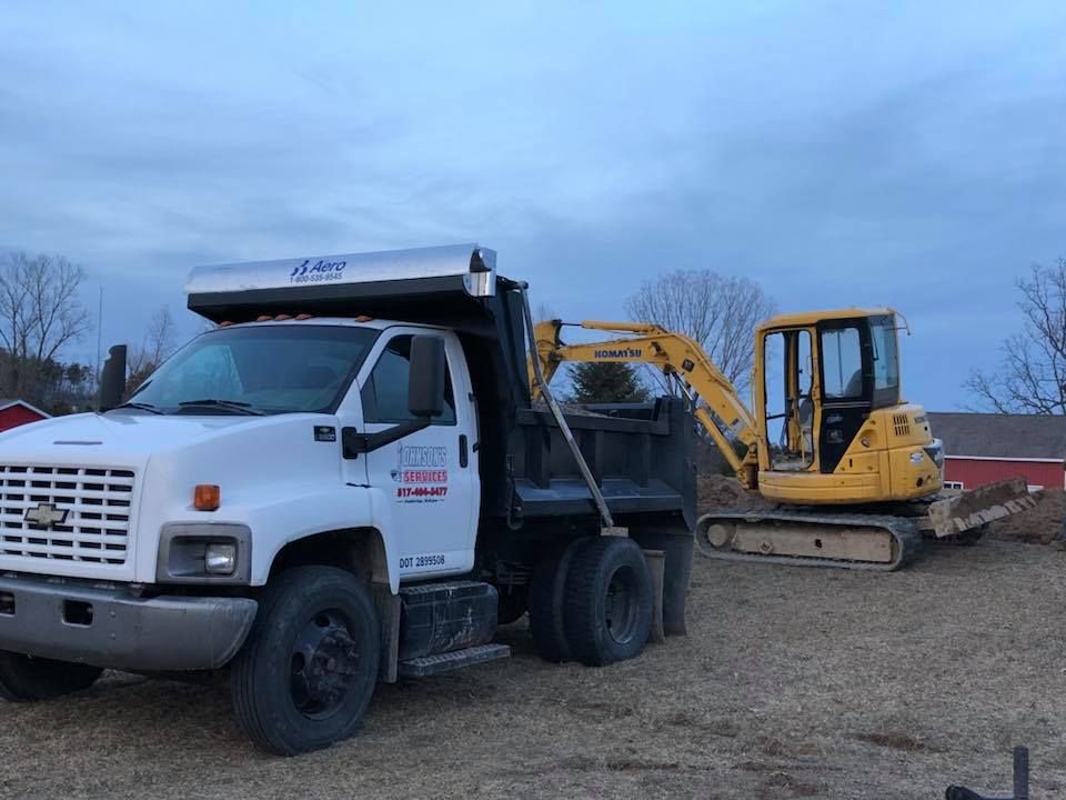 White dump truck parked beside a yellow excavator on a gravel worksite under cloudy sky
