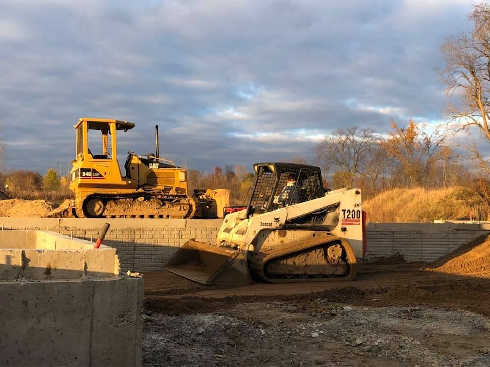 Construction equipment working on a dirt site under a cloudy sky