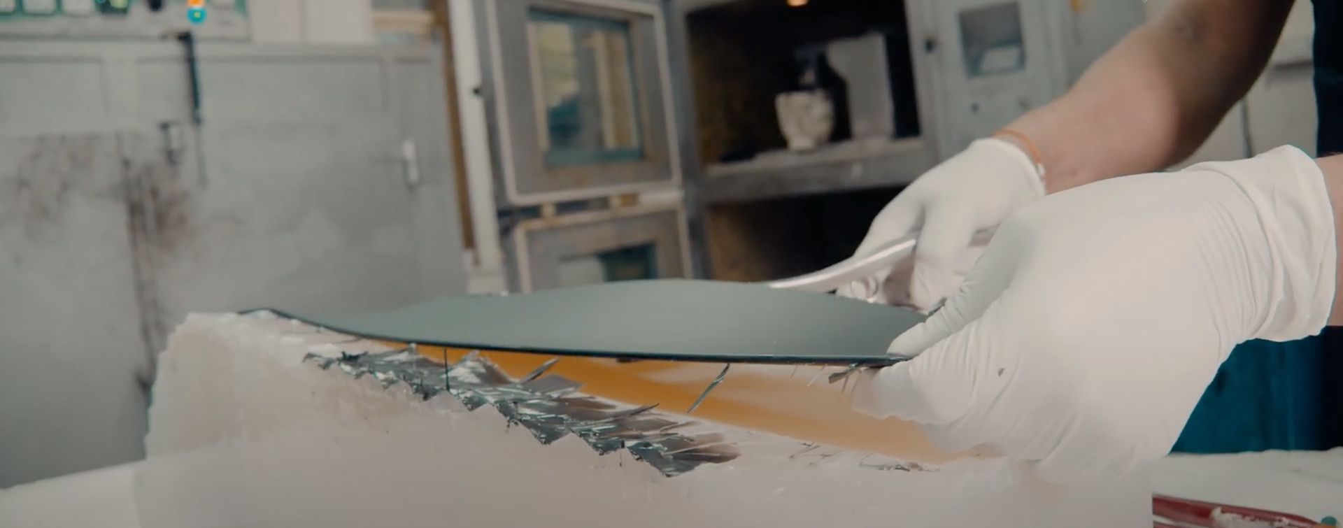 Eine Person mit weissen Handschuhen schneidet ein Stück Papier.