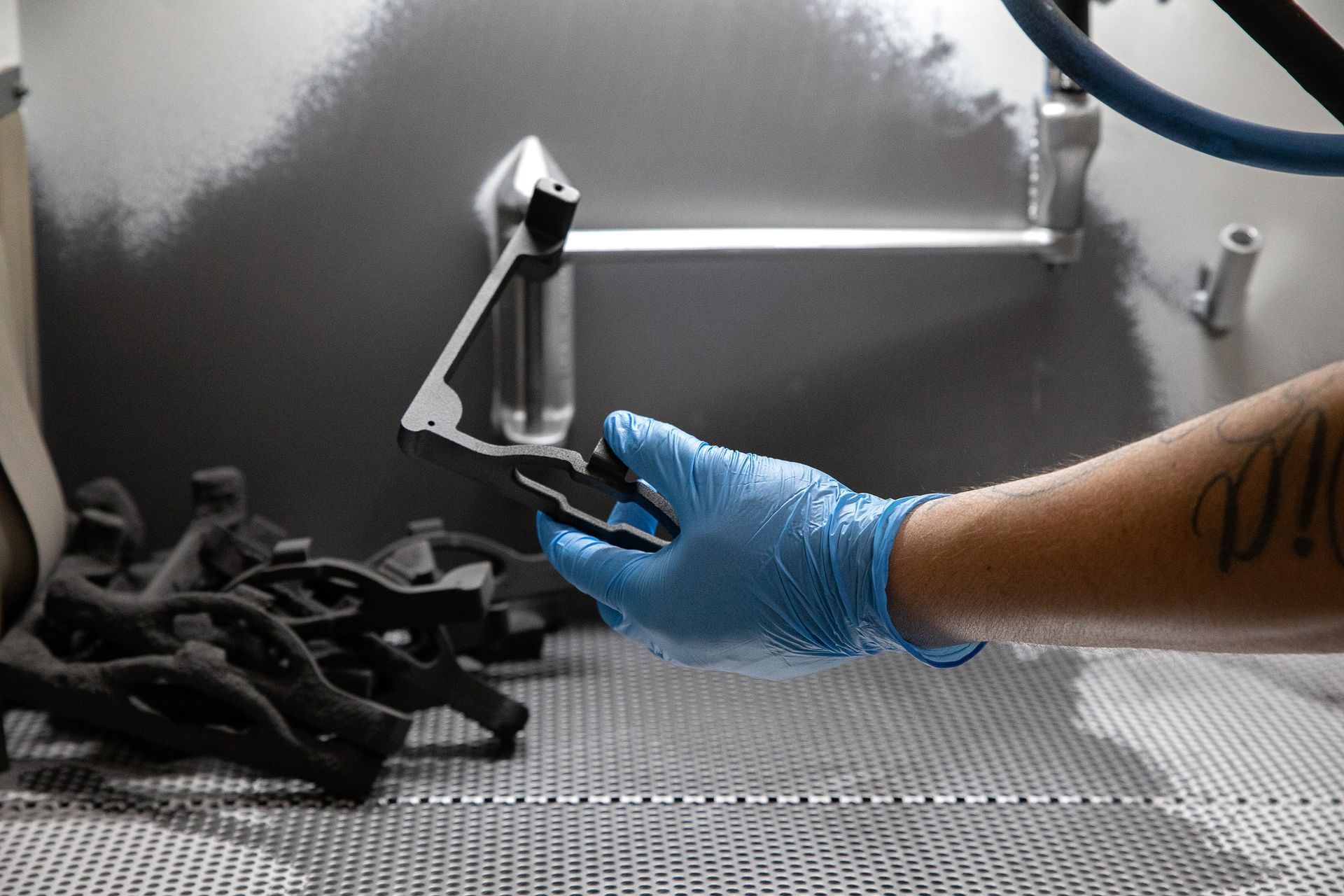 Eine Person mit blauen Handschuhen hält ein Stück Metall in der Hand.