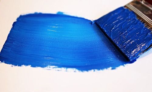 Ein Pinsel mit einem Strich blauer Farbe auf einer weißen Oberfläche.