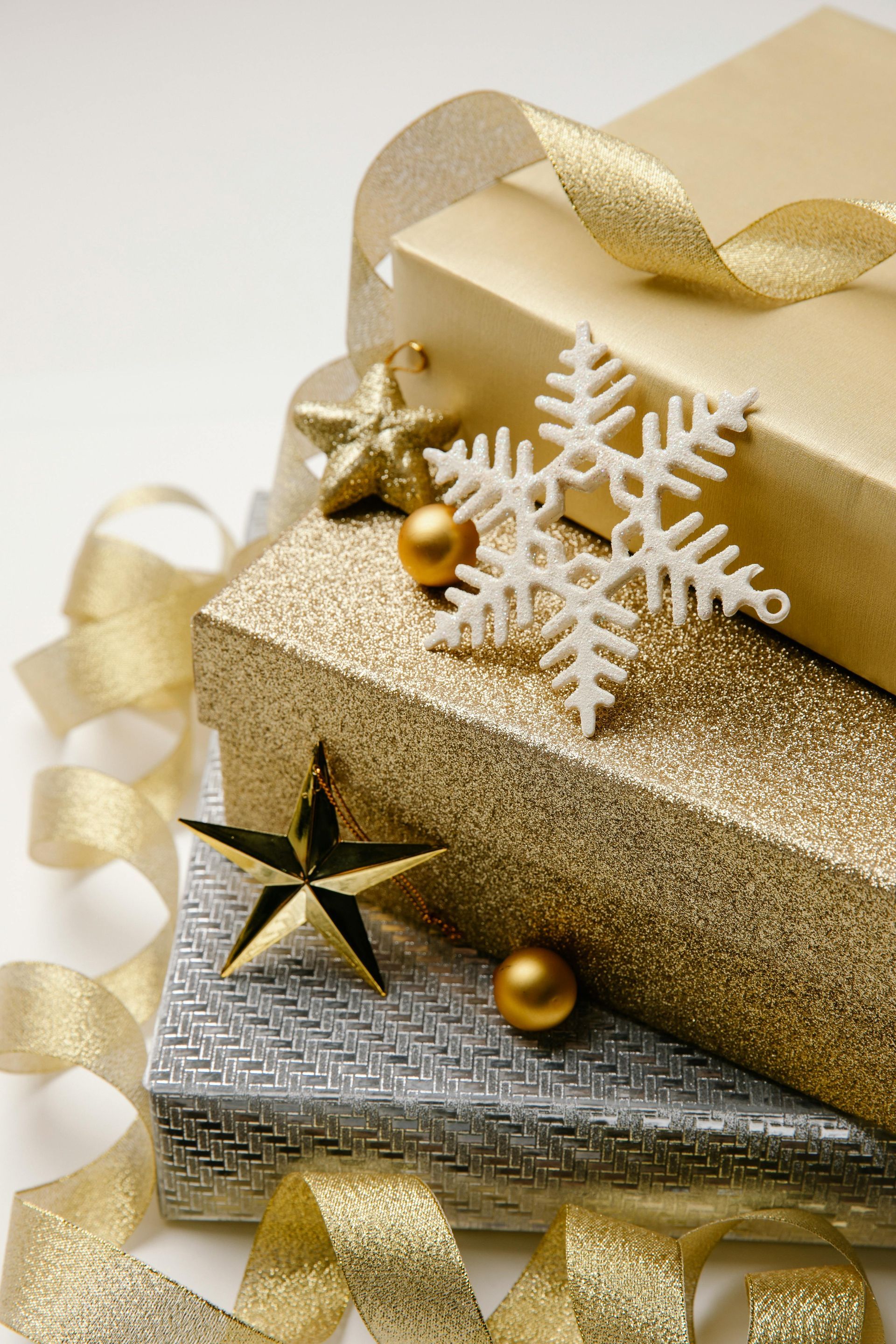 Ein Stapel goldener und silberner Weihnachtsgeschenke mit Schneeflocken und Sternen