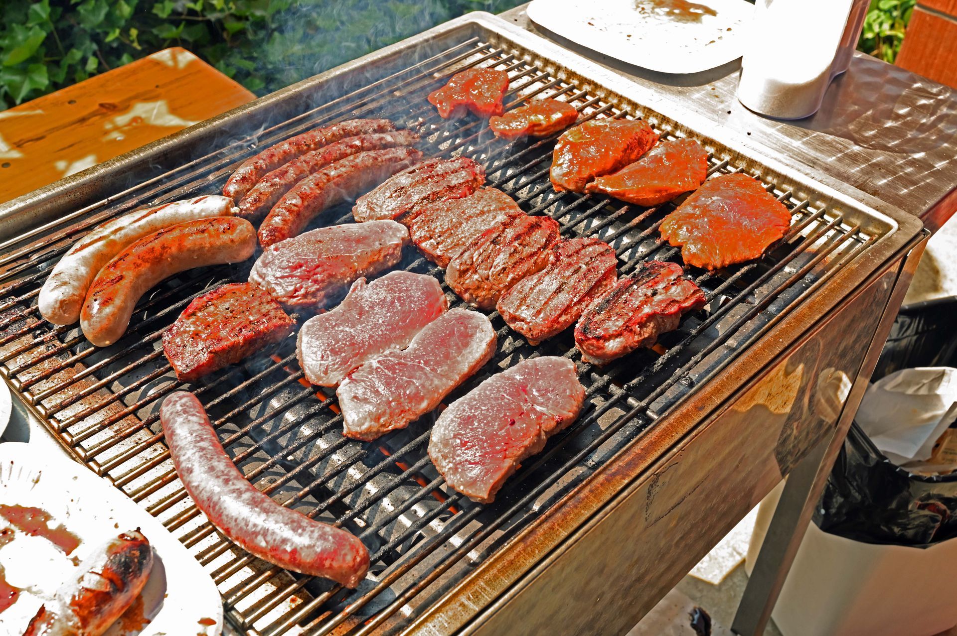 Ein mit Fleisch und Würstchen gefüllter Grill auf einem Tisch.
