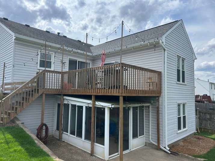 Two-story white house with a wooden deck and exterior stairs over a basement walkout.