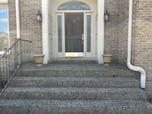 Front entrance with brick steps, black door, and white trim on a brick house