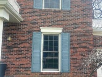Brick house exterior with a white-trimmed window and blue shutters Brick house exterior with a white-trimmed window and blue shutters