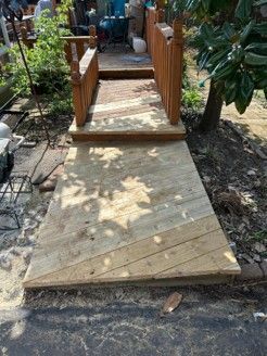 Wooden accessibility ramp with handrails leading up to a garden walkway. Wooden accessibility ramp with handrails leading up to a garden walkway.