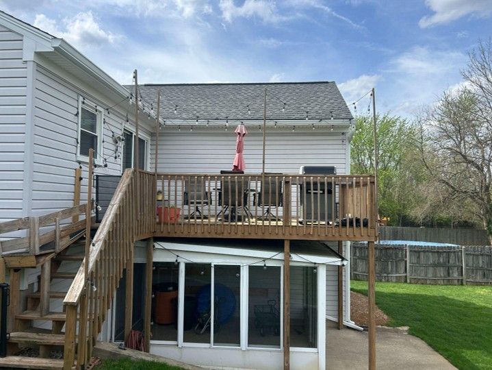 Backyard deck with stairs, patio furniture, umbrella, and sliding glass doors above a sunroom