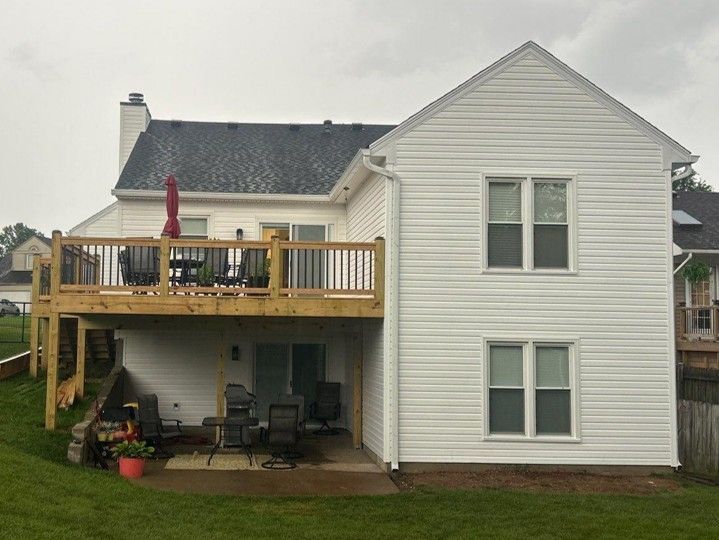 White house with a wooden deck and patio furniture, seen from the backyard.