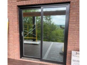 Sliding glass door in a brick wall with a view of a deck and trees outside