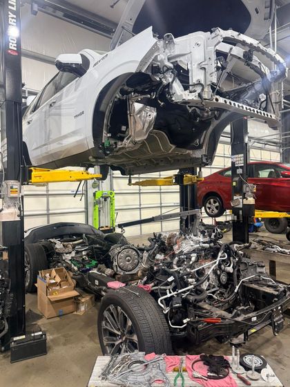 A dismantled vehicle lifted on a hoist above engine parts | Drew's Diesel Repair