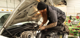 Mechanic inspecting a car engine with the hood open in a garage | Drews Diesel Drew's