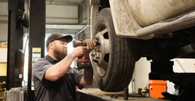 Mechanic using a power tool to remove a car wheel in an auto repair shop | Drew's Diesel Repair