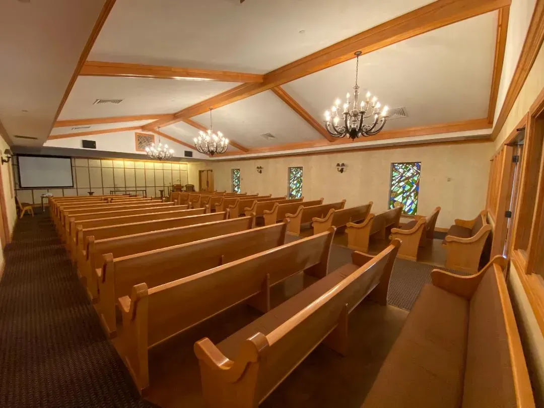 Empty church interior with wooden pews, chandeliers, and stained-glass windows