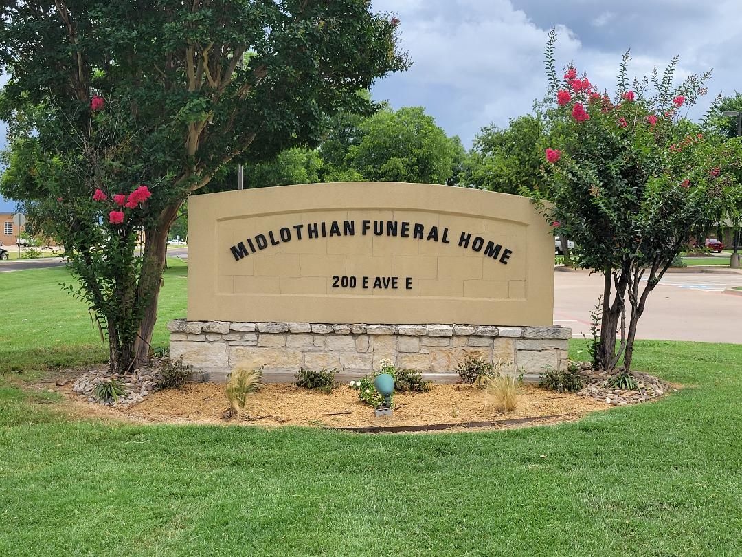 Midlothian Funeral Home stone sign in a landscaped green lawn with trees and flowers