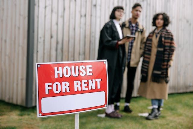 people+standing+behind+house+for+rent+sign