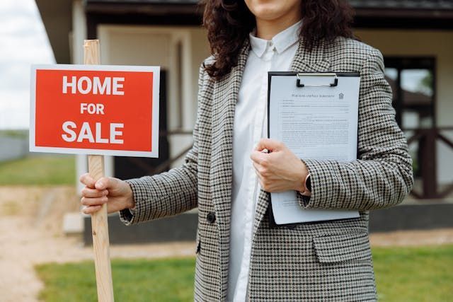 person+holding+a+home+for+sale+sign