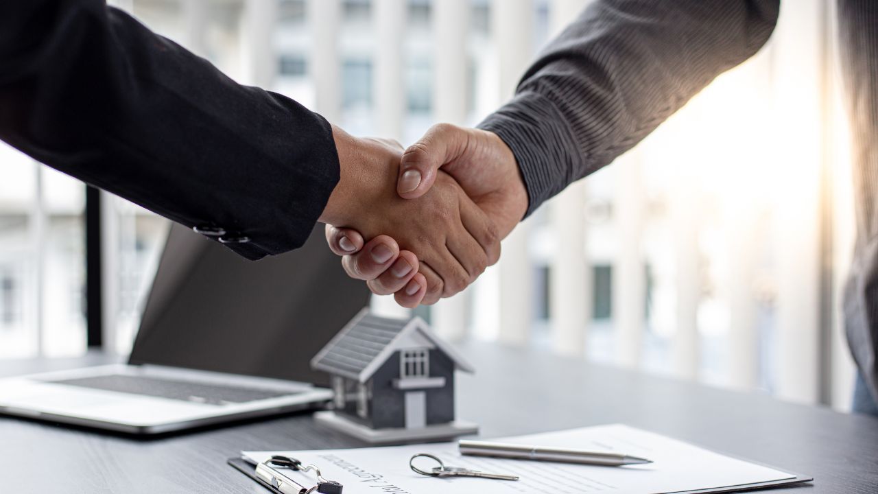 two+people+shaking+hands+over+documents
