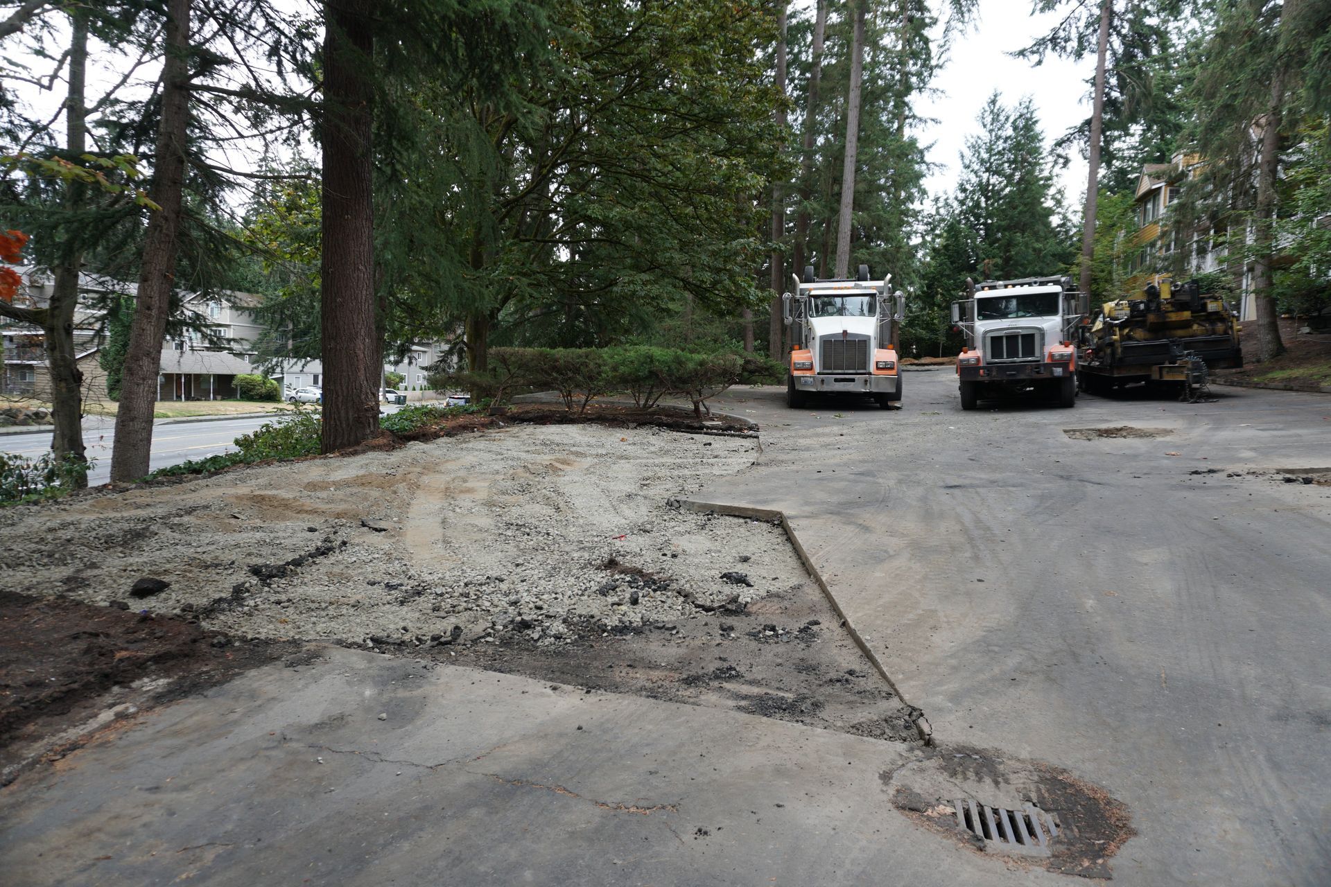 Bobcat skid steer loading asphalt debris into a dump truck on a street.