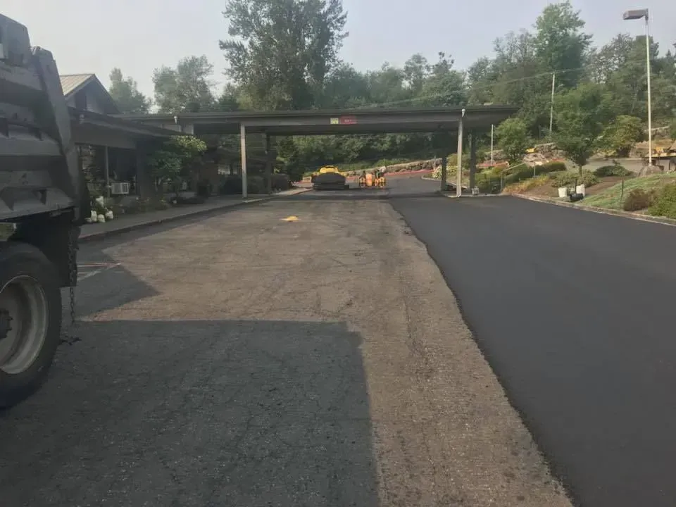 Asphalt paving; partially paved driveway under a covered entrance. Truck on left.