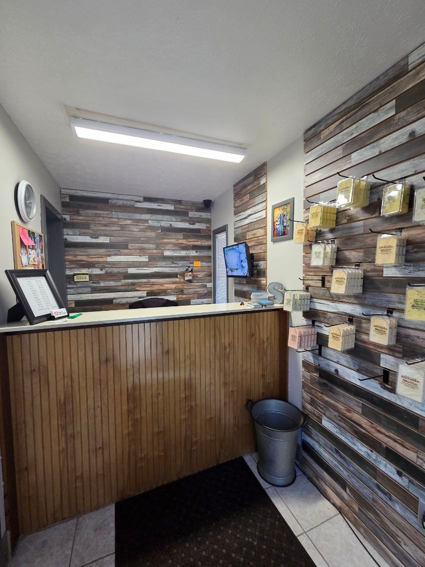 Small reception desk in a modern lobby with wood paneling, wall shelves, and a trash can. Small reception desk in a modern lobby with wood paneling, wall shelves, and a trash can.