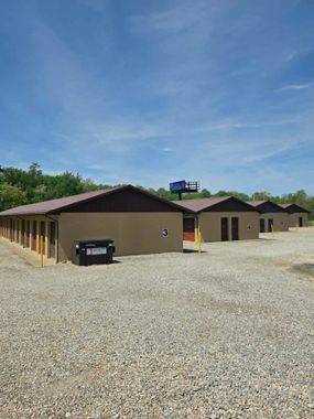 Row of brown single-story buildings on a gravel lot under a blue sky Row of brown single-story buildings on a gravel lot under a blue sky