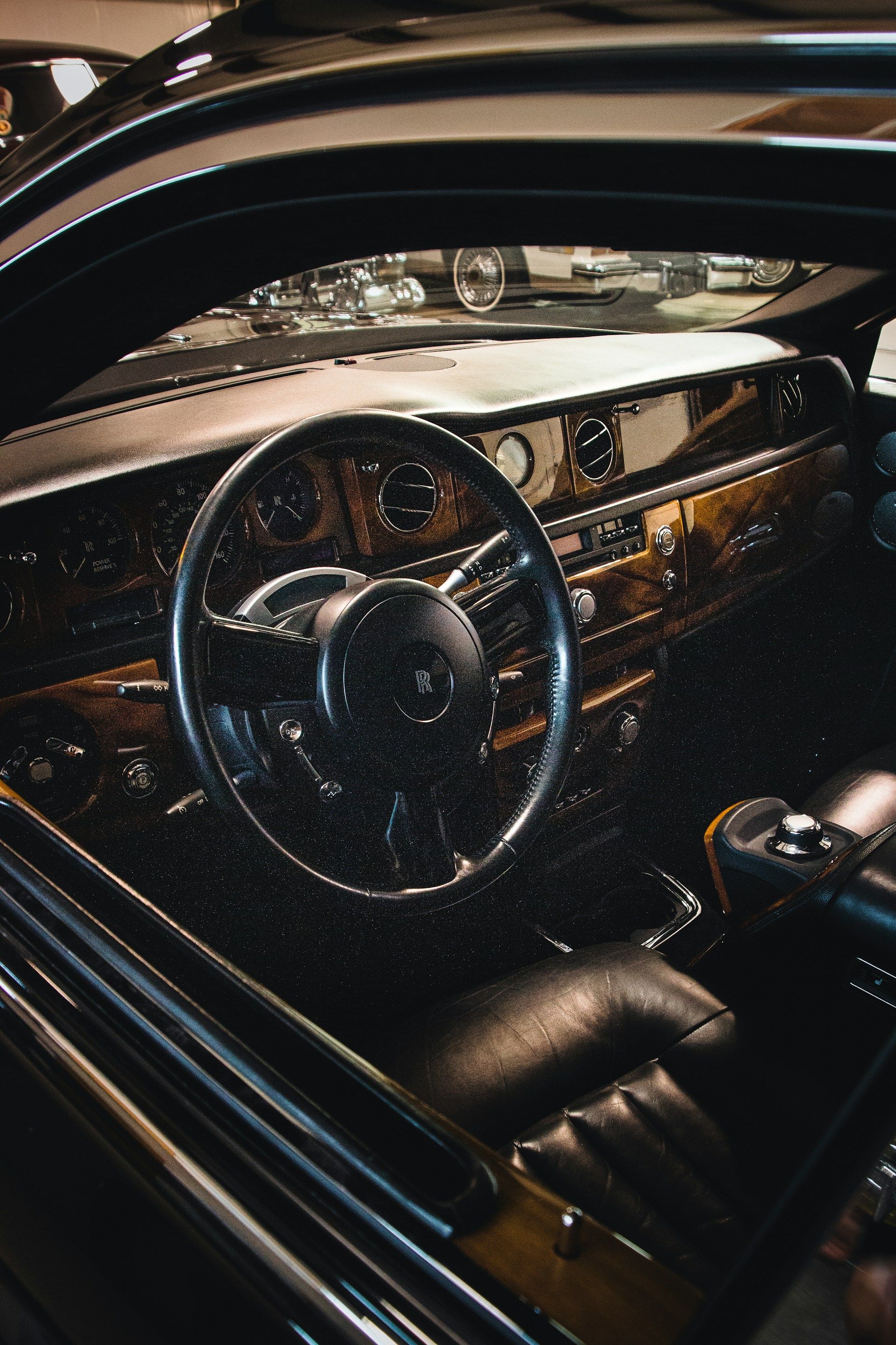 The interior of a luxury car featuring a wood-trimmed dashboard, a black leather steering wheel, and dark leather seats.